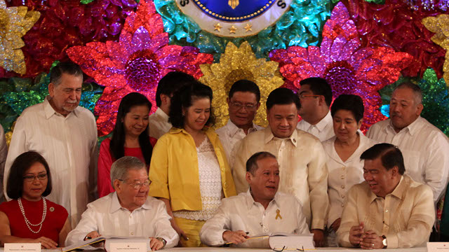 SIGNING: Rep Jocelyn Limcaichong (in red) and Rep Isidro Ungab (behind President Aquino) witness President Aquino sign the 2013 budget. Malacañang file photo 