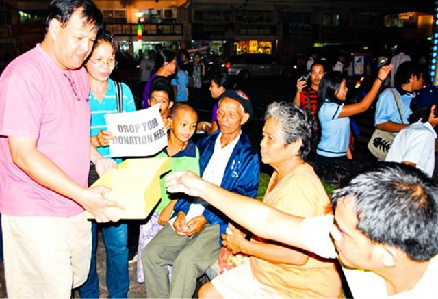 COMMON TOUCH. In a shirt, shorts, and trademark slippers, Jesse Robredo collects donations from the city for Ondoy victims. (Photo from Robredo's Facebook page) 