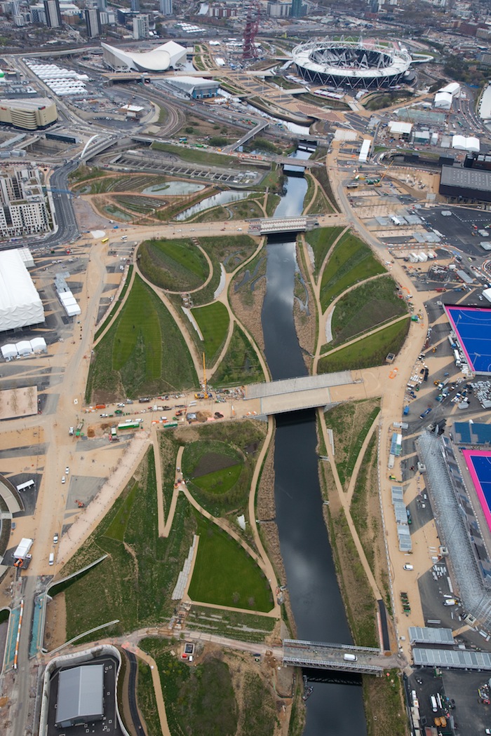 FROM ABOVE. Aerial view of the Olympic Park showing the Parklands looking south towards the Olympic Stadium and Aquatics Center. Courtesy of LOCOG. FROM ABOVE. Aerial view of the Olympic Park showing the Parklands looking south towards the Olympic Stadium and Aquatics Center. Courtesy of LOCOG.