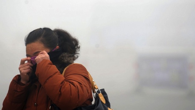 A woman covers her face with her sweater in the heavy smog in Haozhou, central China's Anhui province on January 30, 2013. AFP PHOTO