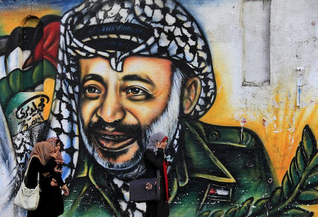LOOMING FIGURE. Female Palestinian students walk in front of a mural showing late Palestinian leader Yasser Arafat in a street of Gaza City. AFP file photo