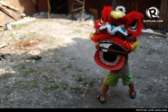 PLAY TIME. A child plays with a 'Shaitao,' the mask used for Dragon Dances