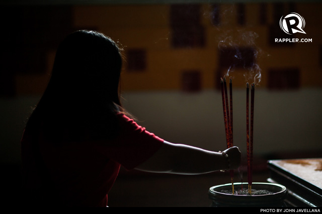 ONLY GOOD KARMA. A woman offers incense inside a Chinese temple 