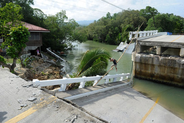BROKEN CROSSING. Using ropes and a bamboo pole, a resident crosses a bridge that was destroyed during an earthquake in the town of Loon in Bohol. Photo by AFP/Jay Directo