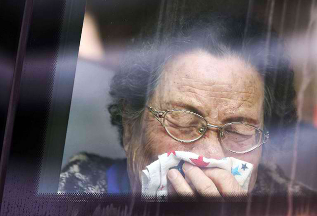 A South Korean woman weeps after bidding farewell to her North Korean relatives, as she sits aboard a bus departing the North Korean resort area of Mount Kumgang. AFP Photo/Yonhap