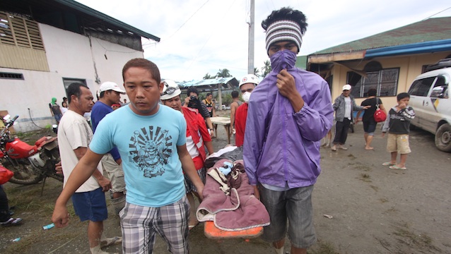 STENCH OF DEATH. Volunteers carrying the bodies cover their mouths due to the foul smell of the rotting corpses. Photo by Karlos Manlupig