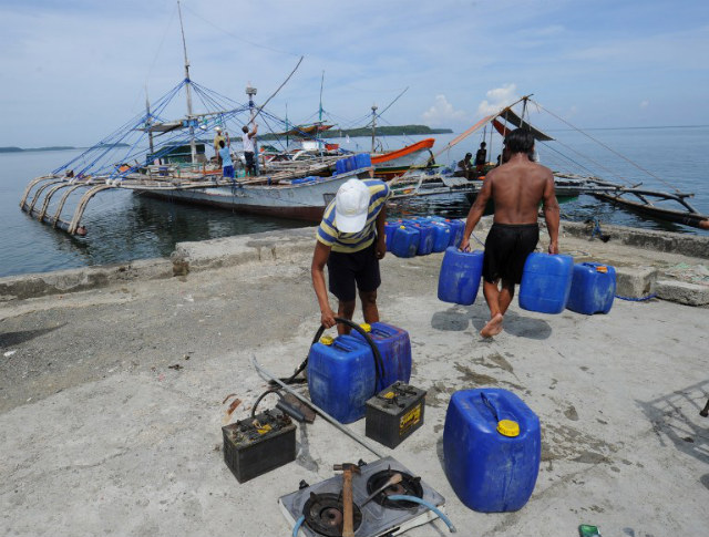 'DECENT LIVING.' Crew members of the fishing boats (back) where a former Philippine Marine officer, as well as his protesters, were set to sail for the disputed Scarborough Shoal, load supplies at a pier in Masinloc town, Zambales province, 230 kilometers from Scarborough on May 18, 2012, after he and his protesters decided to postponed their trip to the disputed shoal. File photo by Ted Aljibe/AFP