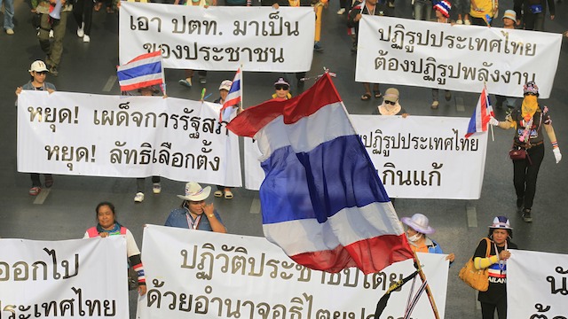 BLOCKING THE VOTE. Thai anti-government protesters hold placards calling political reforms before the elections as they rally to a polling station during advance voting in Bangkok, Thailand, 26 January 2014. Narong Sangnak/EPA