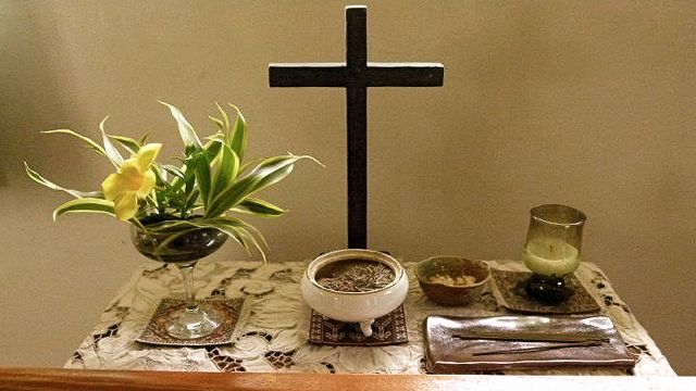 A TYPICAL ZEN ALTAR has flower arrangements, a cross, a Buddha statuette (not in picture), an incense pot, a candle and a kyosaku* stick